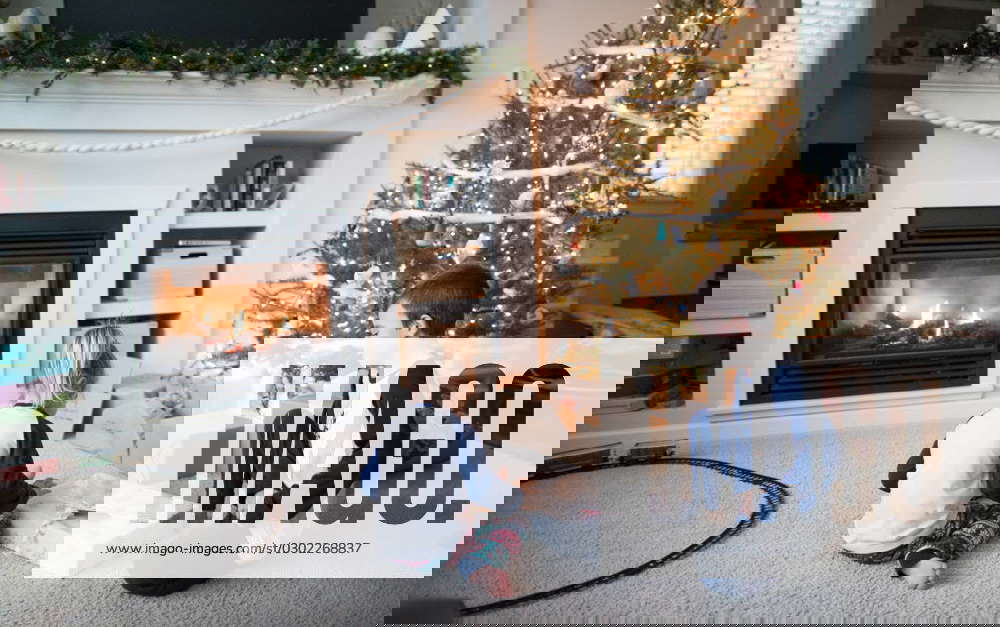 Boy and girl opening gifts together under the Christmas tree Langley