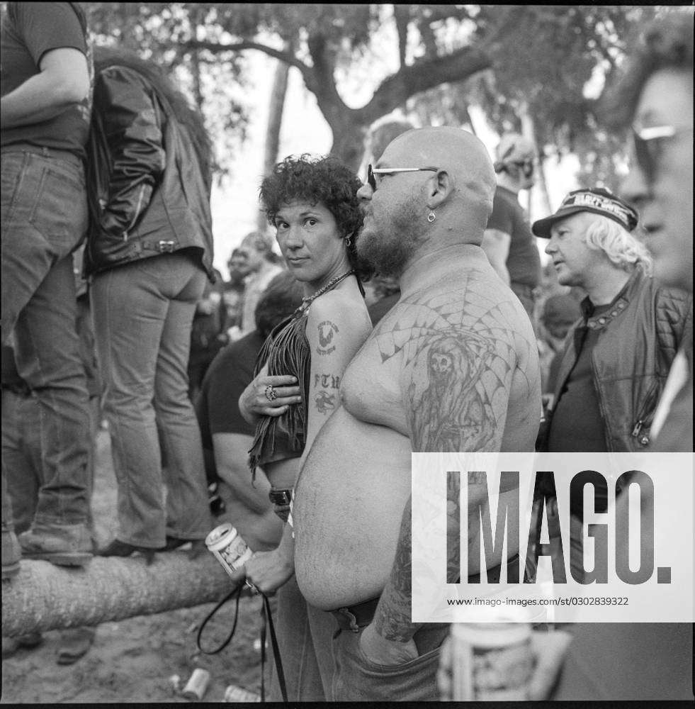 topless fat man displays his tattoos among crowd of bikers during Daytona  Bike Week in March