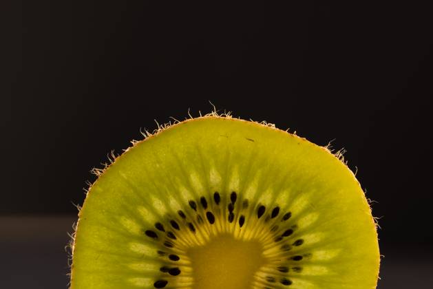 Micro close up of sliced kiwi fruit and copy space on black background ...
