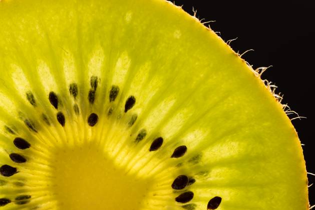 Micro close up of sliced kiwi fruit and copy space on black background ...