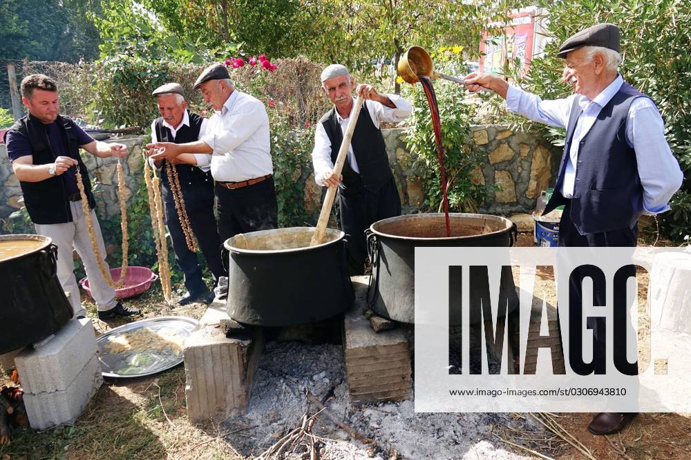 October 1, 2023, Diyarbakir, Turkey Villagers dip walnuts lined up on a rope into grape juice