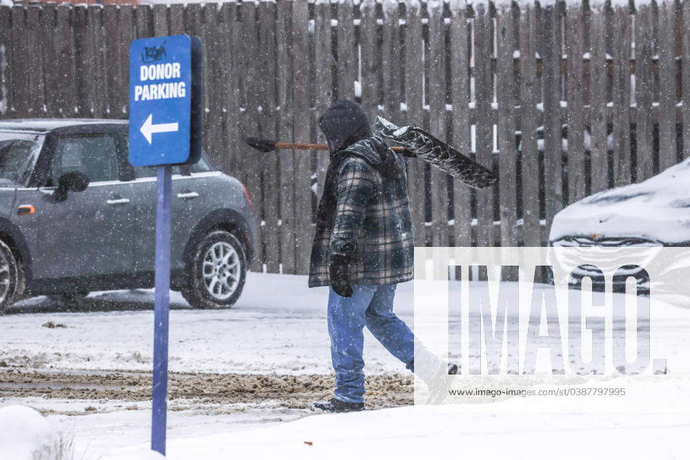 USA, anhaltende Kälte und Schneestürme in Iowa A man carries a snow ...