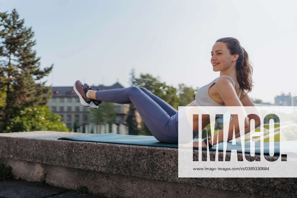 Side view of young sporty woman doing elevated crunches on gym mat in ...