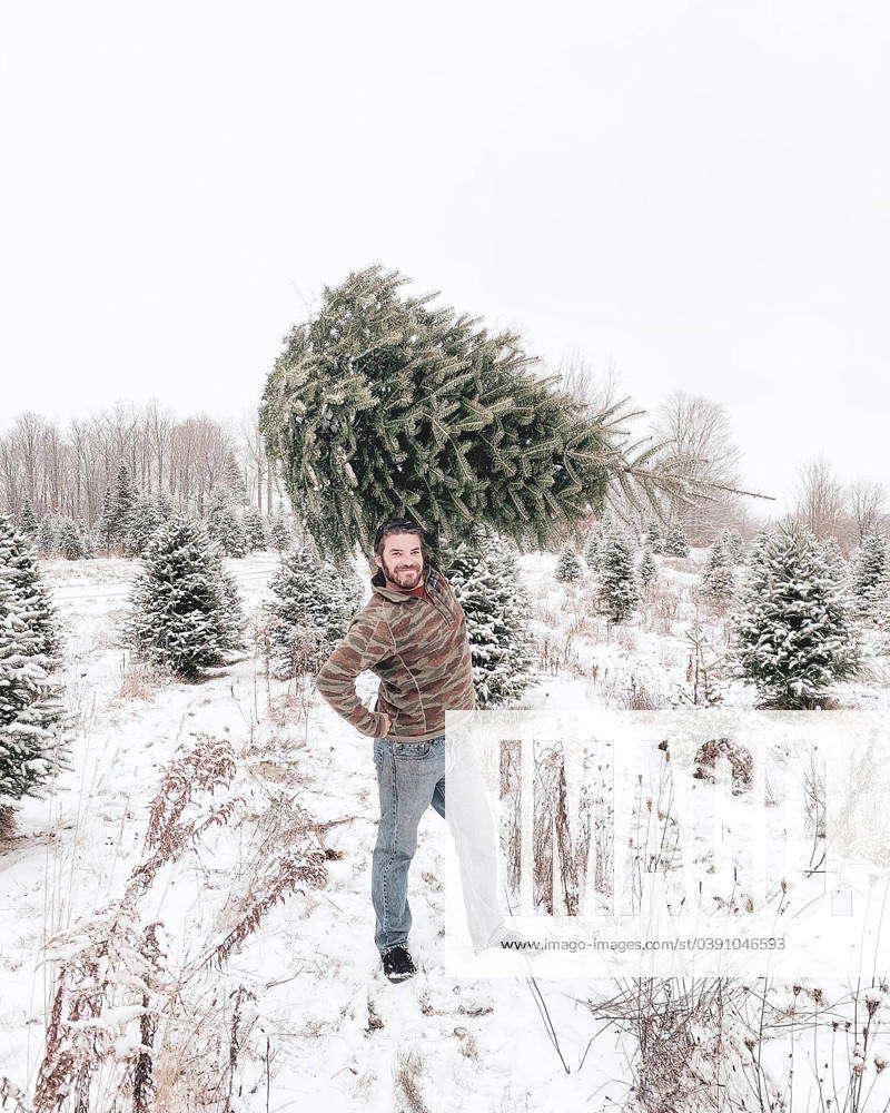 Man holding Christmas Tree Over Head Outside in Snow Dushore