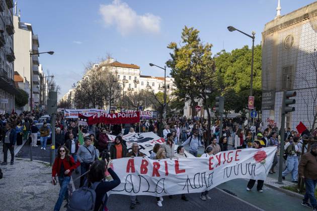Protesters marching in the streets of Lisbon with banners and signs.