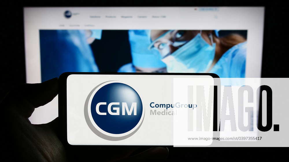 Person holding mobile phone with logo of company CompuGroup Medical SE ...