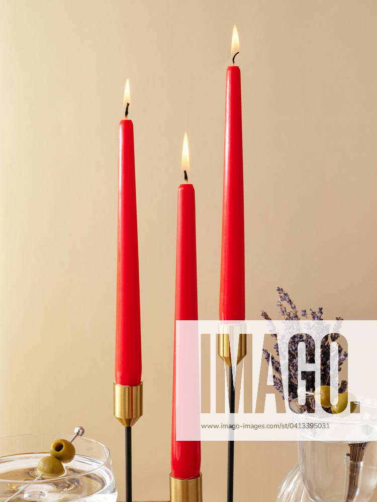 Candles stand on the table in tall metal candlesticks. festive t