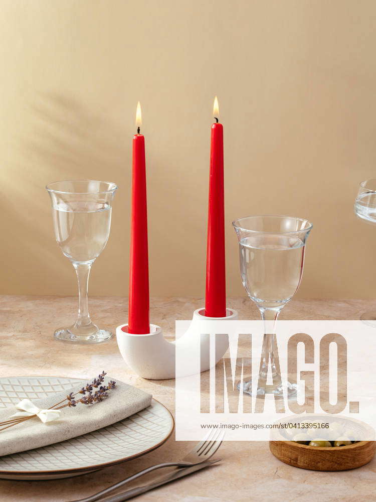 Candles stand on the table in a tall stone candlestick. the tab