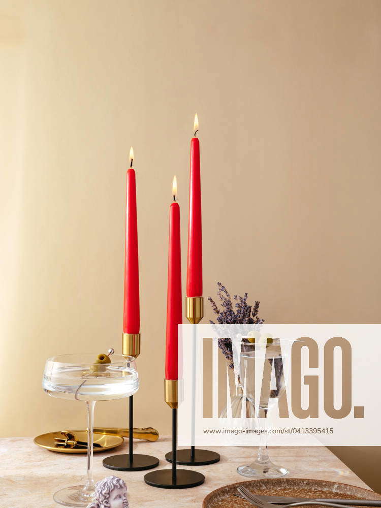 Candles stand on the table in tall metal candlesticks. festive t