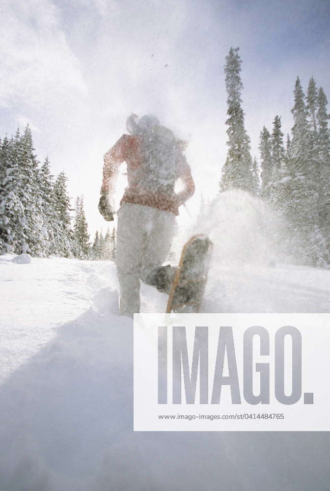 A woman snowshoeing by Spray Lakes, in Peter Lougheed Provincial Park