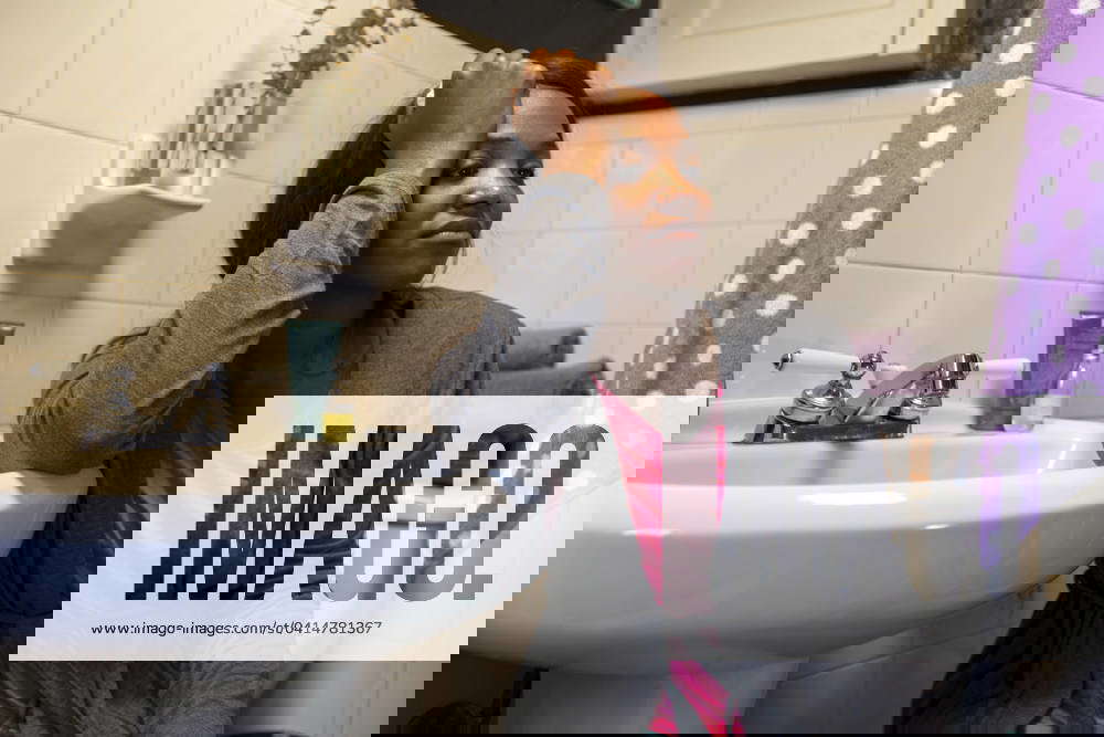 Young woman in the bathroom feeling ill, contemplating staying home