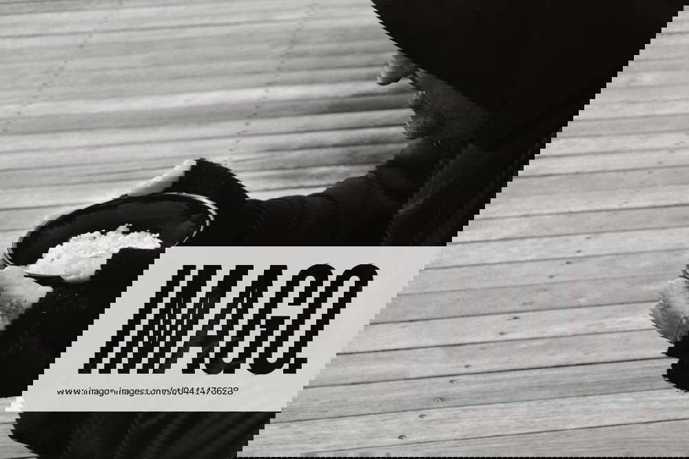 Homeless person holding a bowl of rice in community food kitchen PERTH