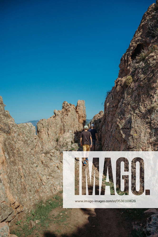 Two boys hiking in Corsica s rugged mountains overlooking the sea Piana ...