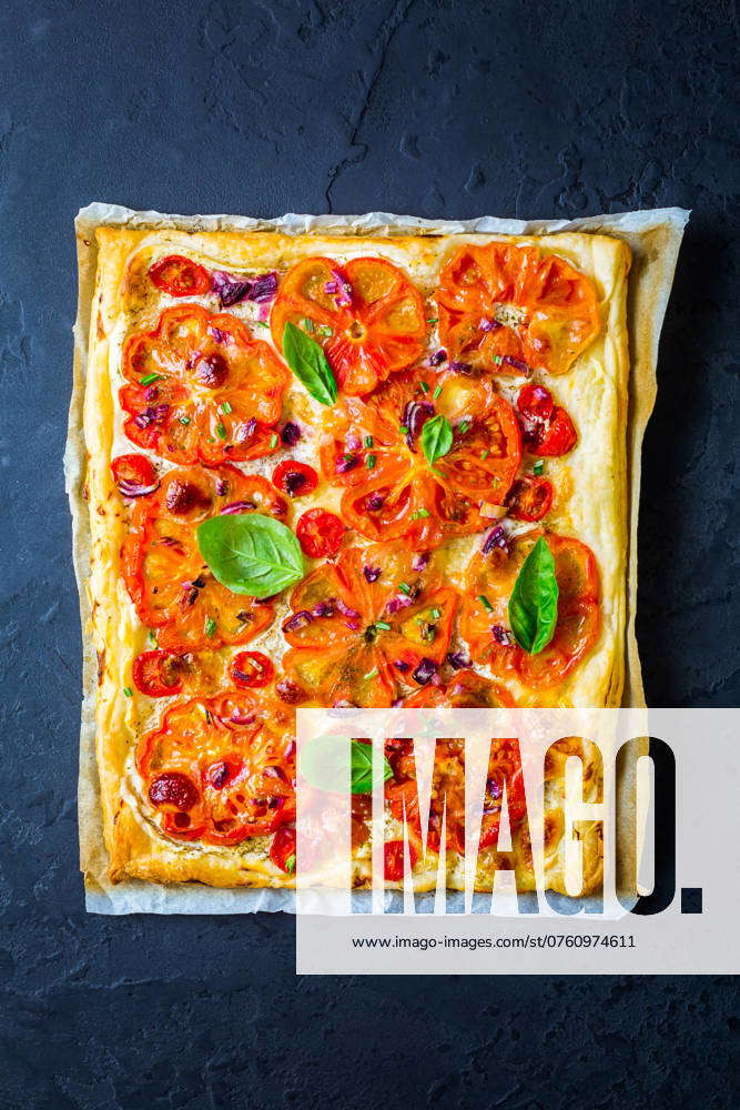 Vegetarische Tomatentorte oder Puffpizza mit Kräutern auf schwarzem ...