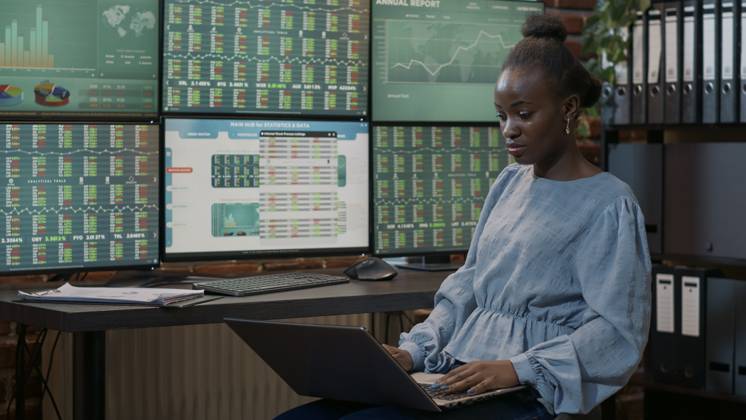 Multiple Monitor Banking Video: Female investor looking at real time stocks on laptop and ...
