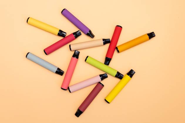 Disposable e-cigarettes, different flavors in orange. The concept of ...