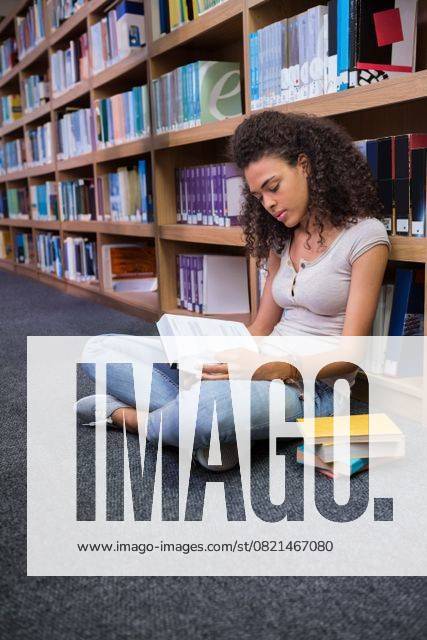 African American woman wearing jeans sitting on floor in library ...