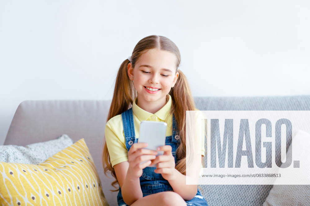 Girl using her cell phone sitting on sofa Free Time. Portrait of ...