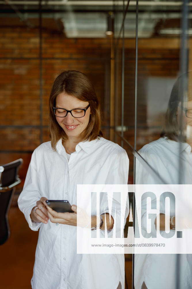A Smiling Woman Using a Smartphone in a Modern Office, Radiating ...