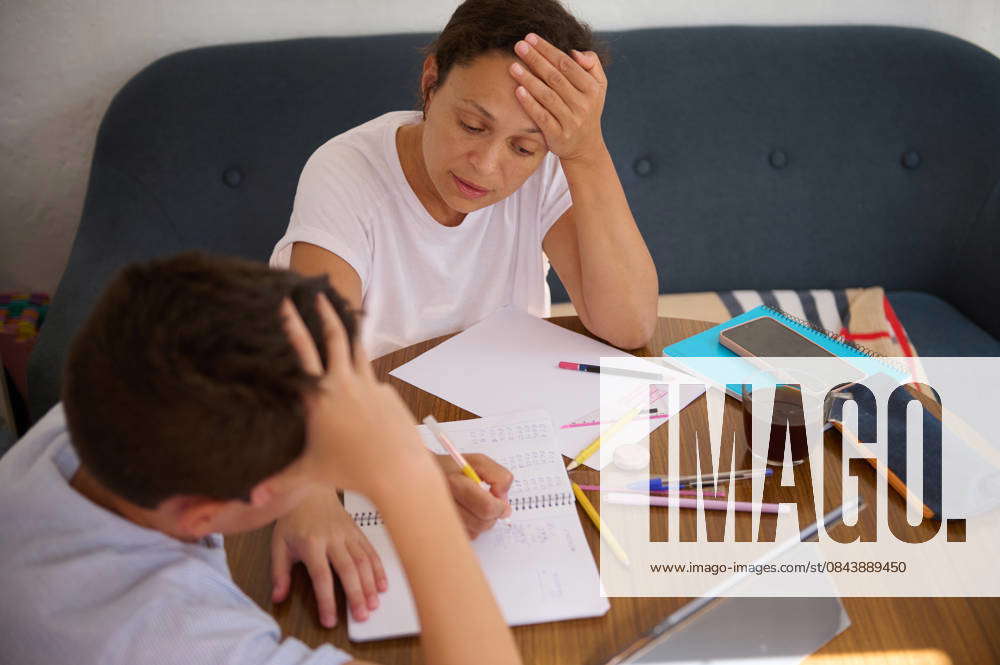 Mother helping son with homework while feeling stressed A mother and ...